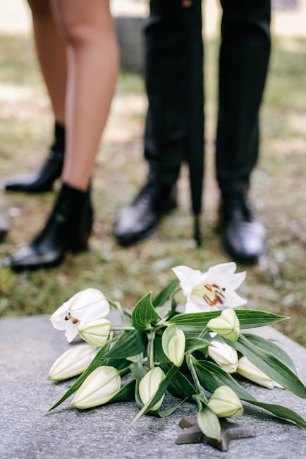 A bouquet of fresh white lilies and unopened lily buds arranged with green foliage, lying on a stone surface outdoors. The bouquet includes large, open lily blooms with white petals and prominent redd